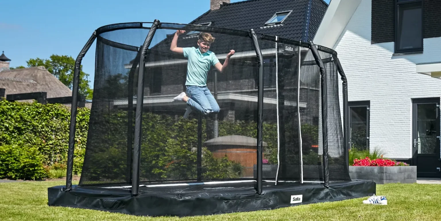 Dreng hopper på firkantet trampolin i haven